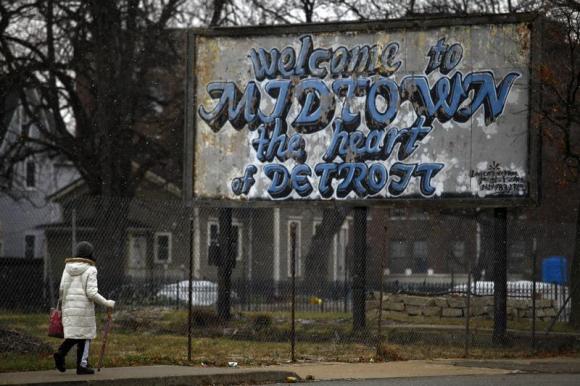 A woman walks through the Midtown neighborhood of Detroit