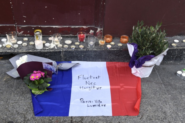 Flowers, candles and the French national flag with the Latin, "Tossed but not sunk" the motto of Paris written on it, is laid outside of the Carillon, adjacent to the Cambodian restaurant on Rue Alibert in the 10th district, of the French capital Paris, on November 14, 2015, the morning after an attack which killed 12 people at the restaurant. Islamic State jihadists claimed a series of coordinated attacks by suicide bombers and gunmen in the city that killed at least 128 people at a concert hall, restaurants and the national sports stadium. AFP PHOTO / DOMINIQUE FAGET (Photo credit should read DOMINIQUE FAGET/AFP/Getty Images)