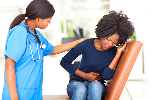young african nurse comforting female patient in doctor's office