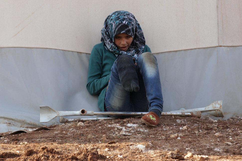 An internally displaced Syrian girl with an amputated leg checks her phone at the Bab Al-Salam refugee camp, near the Syrian-Turkish border, northern Aleppo province, Syria January 19, 2017. REUTERS/Khalil Ashawi